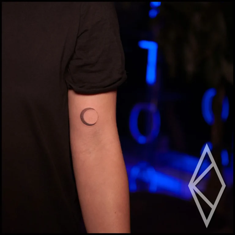 Small tattoo of a moon on upper arm, fineline