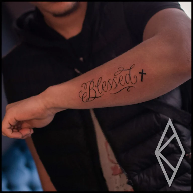 Word blessed tattooed on forearm in finline lettering