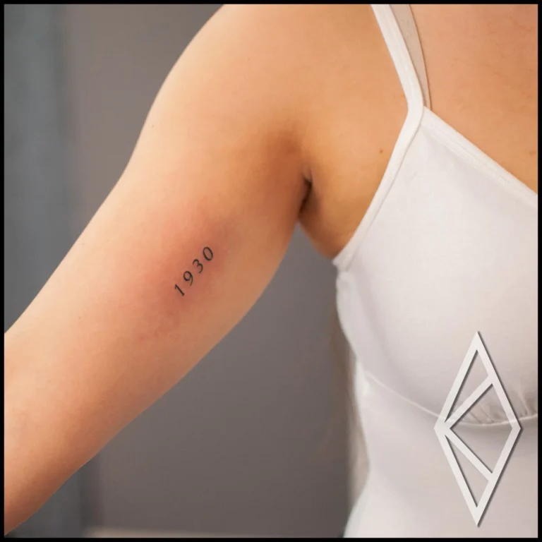 Small text tattoo on inner bicep, year of birth